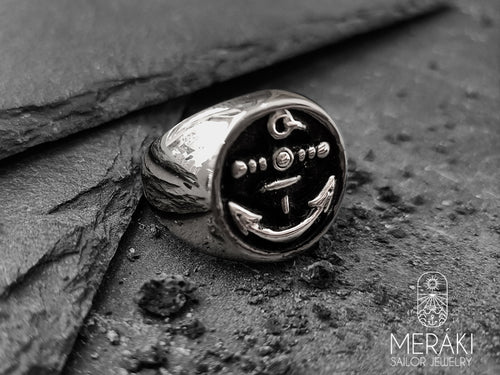 Anello in acciaio Atabey by Meraki Jewelry con ancora centrale su sfondo nero