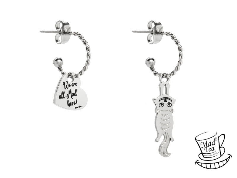 Orecchini con anelle con gatto di Alice appeso e ciondolo a forma di cuore con incisa la frase “We are all Mad here!” ossia “Siamo tutti matti qui!”.