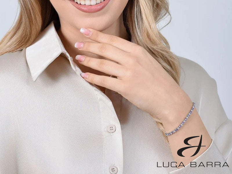 Bracciale tennis Donna in acciaio con cristalli viola e bianchi. I cristalli viola, simbolo di nobiltà e creatività, si uniscono alla purezza dei cristalli bianchi, creando un effetto di regalità radiante. Un gioiello che aggiunge un tocco di lusso e nobiltà al tuo stile quotidiano, perfetto per esprimere la tua eleganza intramontabile e la tua presenza sofisticata.