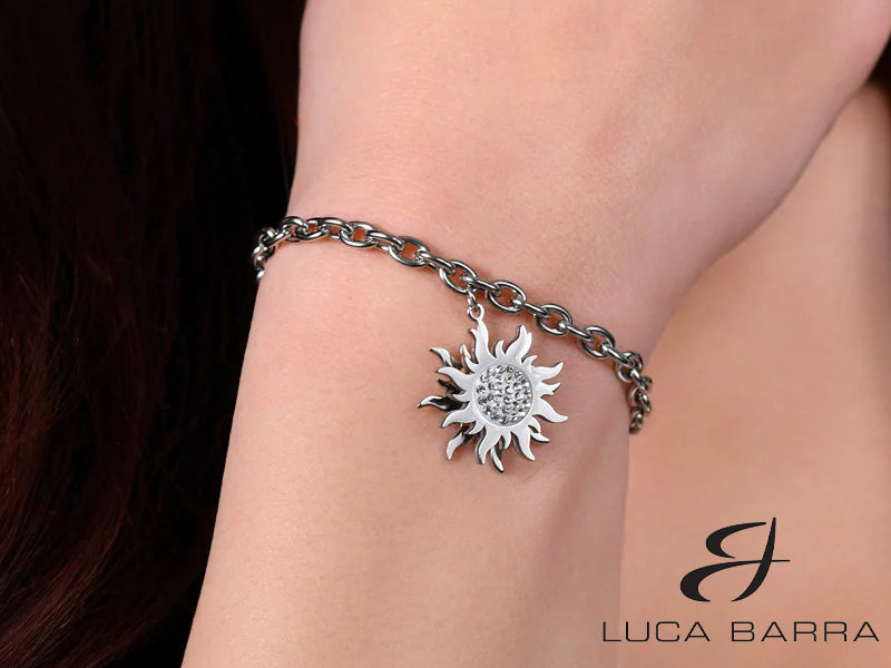 Il design elegante di questo bracciale presenta un pendente a forma di sole girevole, simbolo di energia, vitalità e ottimismo, arricchito da cristalli bianchi scintillanti che brillano con ogni movimento. Questo simbolo solare è più di un semplice accessorio; porta con sé un significato di gioia, speranza e nuova vita.