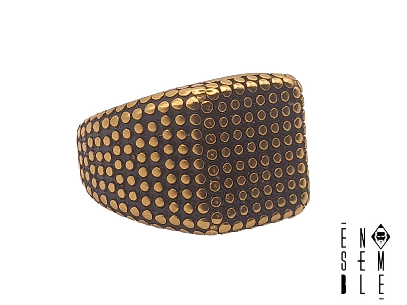 Anello uomo Chevalier quadrato con borchie in acciaio dorato e brunito. Il contrasto dell'acciaio dorato lucido con la parte brunita rende questo anello una lezione di stile.