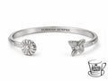 Bracciale regolabile in acciaio inossidabile, luminoso e pensato per avvolgere delicatamente il polso. Il modello è decorato con farfalla e margherita tridimensionali e custodisce all’interno la scritta “SORRIDI SEMPRE”. 