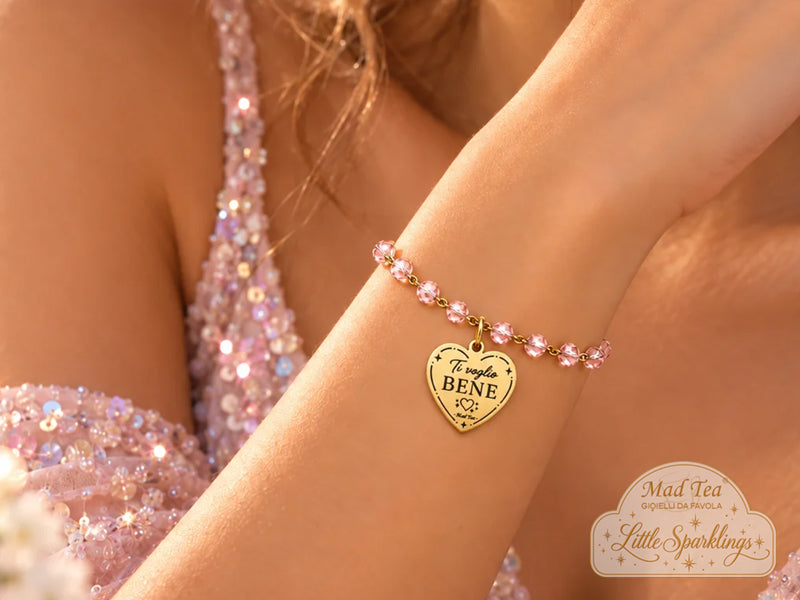 I cristalli rosa gli regalano una luce delicata e femminile, mentre il ciondolo a cuore con la scritta “Ti voglio bene” racchiude un messaggio piccolo solo nelle parole, ma enorme nel significato.