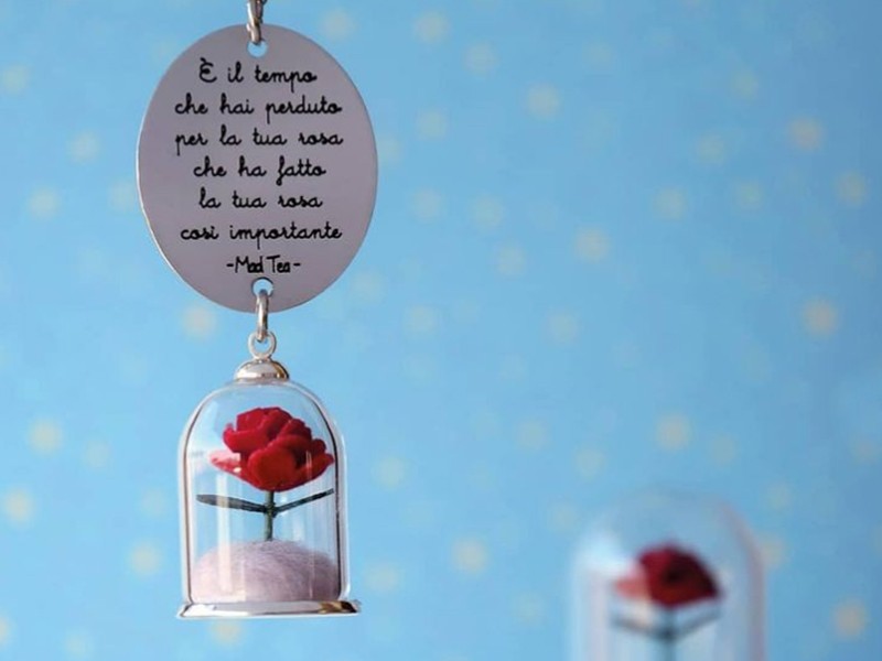 Collana con rosa del Piccolo Principe contenuta in una campana di vetro e targhetta con incisa la frase "È il tempo che hai perduto per la tua rosa che ha fatto la tua rosa così importante”. Catena a rosario.