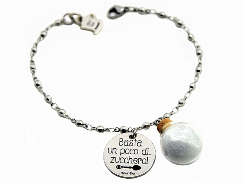 Il bracciale Basta un poco di zucchero è dedicato alla stravagante tata Mary Poppins, che con la sua borsa e il suo ombrello sa catapultarti nel suo magico mondo. È in acciaio anallergico, formato da una catena a pallini alternati e due ciondoli: uno è un dischetto piatto con incisa la frase “Basta un poco di zucchero” e la sagoma di un cucchiaino, l’altro è una boccetta in vetro anti urto con dello “zucchero”.  