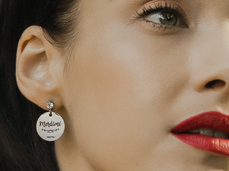 "Posso resistere a tutto, tranne alle tentazioni!"  L'iconica mela avvelenata diventa, in questa serie di gioielli, un simpatico simbolo di ironia giocando con la parola "Mordimi".