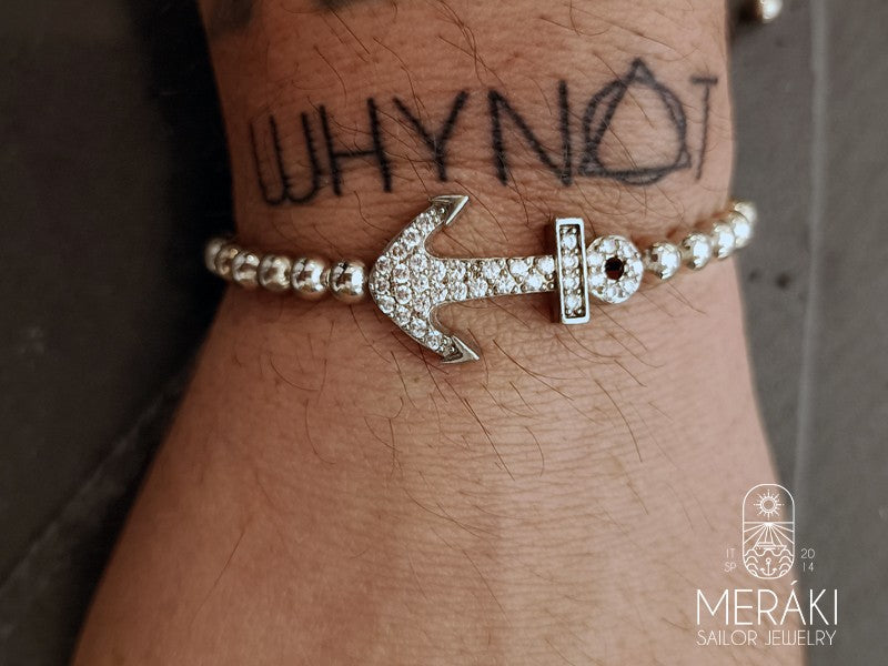 Bracciale realizzato in cotone cerato nero rivestito da perline con charm a forma di ancora in acciaio inossidabile indossato