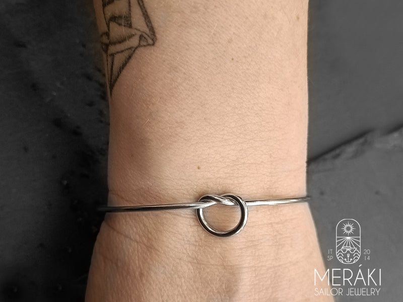 Bracciale rigido Bangle in acciaio con nodo simbolo per eccellenza di unione, del legame tra una o più persone, qualunque essa sia e chiunque essi siano. 