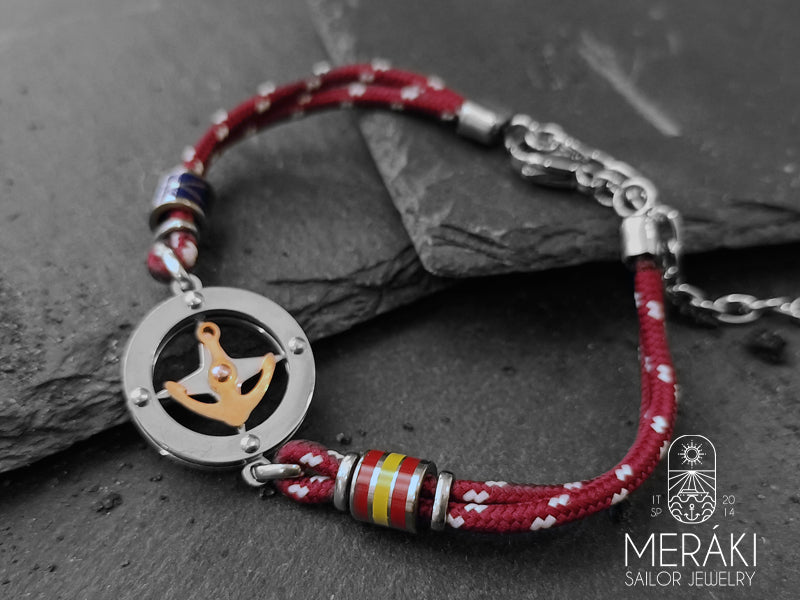 Un braccialetto colorato è la giusta soluzione per vivacizzare anche gli outfit maschili più formali e da ufficio, Noah è realizzato con cordino nautico bicolor rosso e charm centrale con rosa dei venti e ancora dorata girevole a contrasto