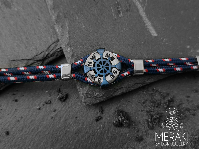 Questo bracciale da uomo presenta un charm con timone realizzato in acciaio inossidabile chirurgico blu con i punti cardinali a contrasto. 