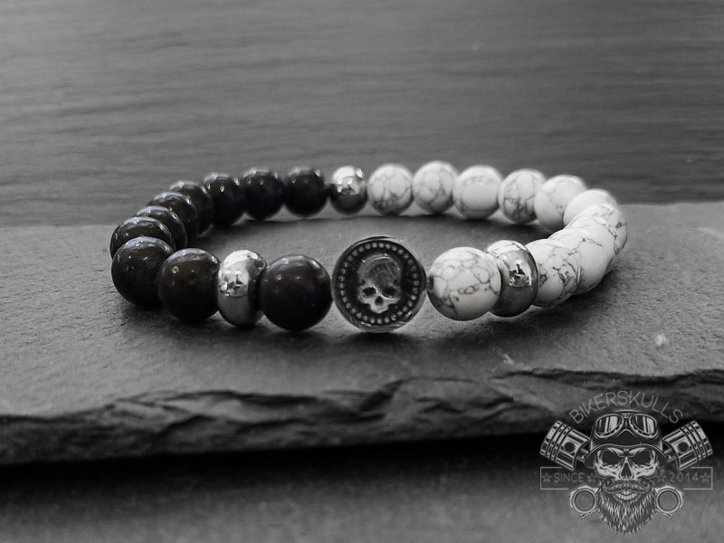Elegante e raffinato bracciale da uomo realizzato con pietre naturali di Onice nera e Howlite. A completamento del bracciale il charm centrale rotondo con teschio in acciaio inossidabile
