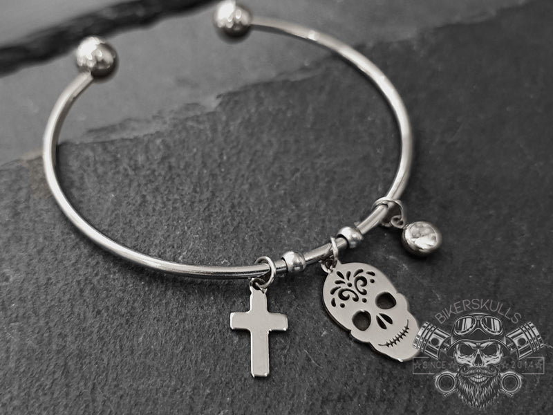 Il bracciale Kodama bangle piercing presenta un teschio messicano, una croce e un piccolo punto luce in acciaio altamente dettagliati e simboleggia la resilienza che dà alla donna audace la capacità di resistere coraggiosamente a tutto ciò che la vita gli lancia.