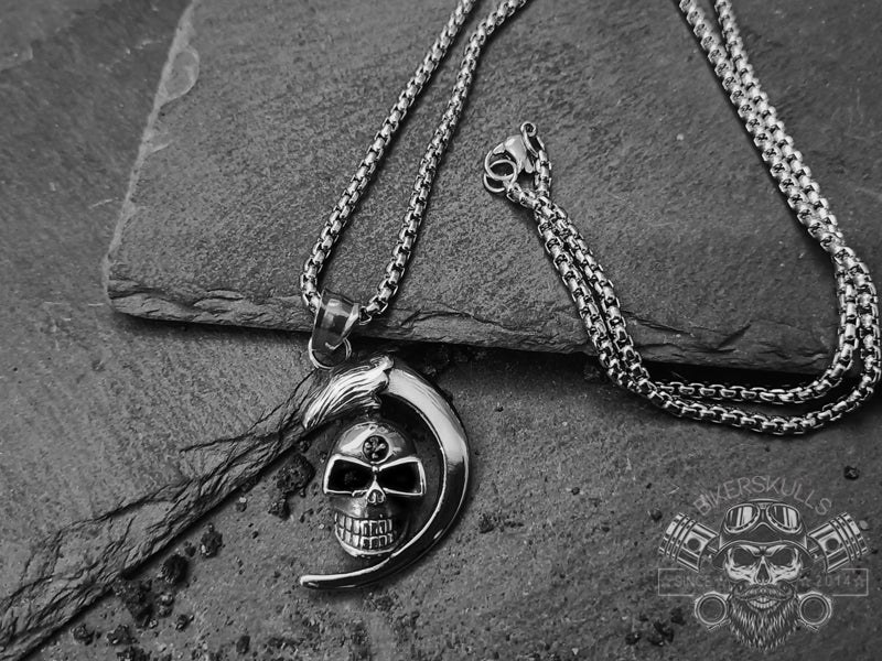 Collana Caratterizzata da un ciondolo con teschio e luna crescente che si fissa su una catena in resistente acciaio e da una pratica chiusura a moschettone.