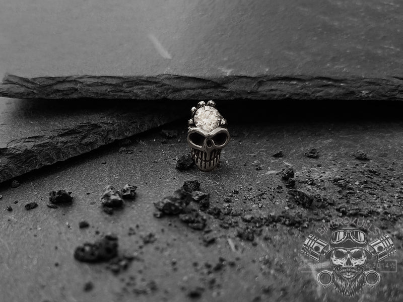 Orecchino dal design a teschio sul quale è incastonata una pietra zirconia cubica trasparente che crea un look a contrasto molto elegante.