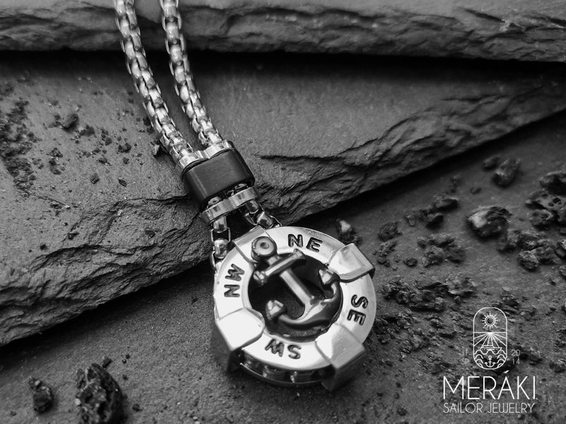 Collana in acciaio inossidabile lucidato, dal design insolito. Il pendente a cappio è a forma di àncora, al di sotto della quale figurano i punti cardinali che rendono ancor più maschile questa collana.