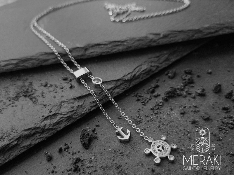 Collana ealizzata con maglia fine in acciaio e pendenti regolabili tramite cappio raffiguranti l'ancora e il timone con zirconi 
