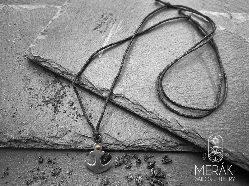 Collana realizzata con cordino cerato regolabile e pendente raffigurante un'ancora in acciaio, impreziosita da dettagli in acciaio dorato