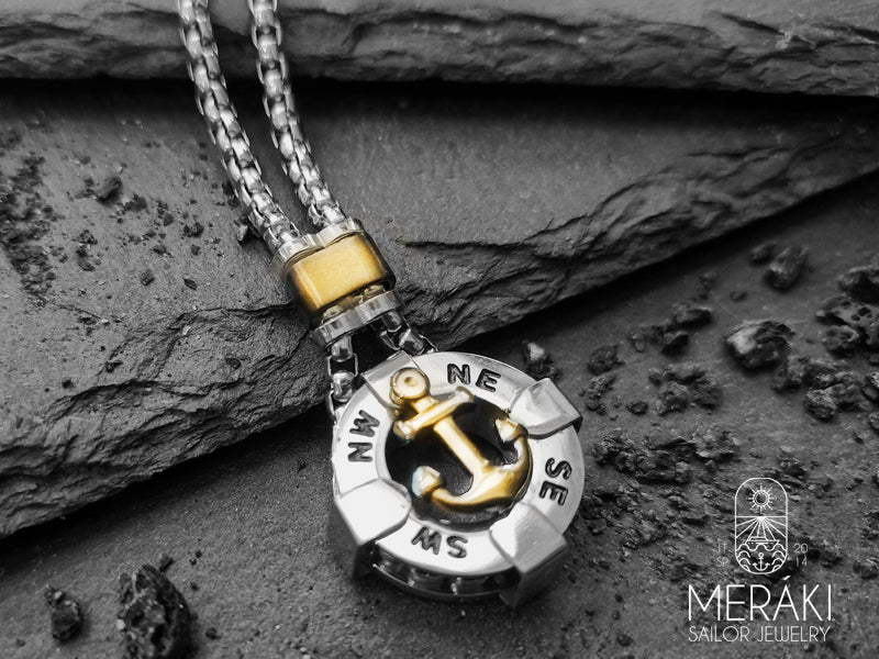 Collana in acciaio inossidabile lucidato, dal design insolito. Il pendente a cappio è a forma di ancora dorata, al di sotto della quale figurano i punti cardinali che rendono ancor più maschile questa collana.