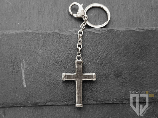 Un pendente a forma di croce borchiata, una catena e un anello portachiavi con moschettone realizzati in acciaio inossidabile resistente caratterizzati da un'alta lucentezza.