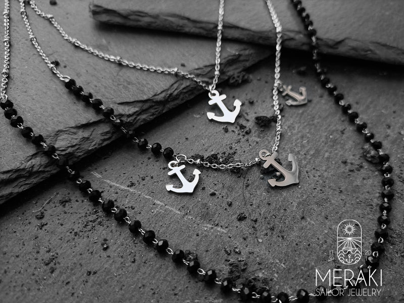 Struttura a tre maglie che alterna un elemento dal pattern diamantato  a una fila tipo rosario con pietre naturali e una maglia classica forzatina. Completano e rendono il design marinaro quattro ancorette in acciaio