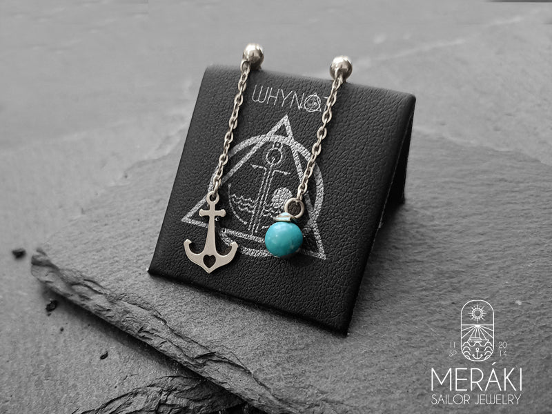 Orecchini asimmetrici a perno con catenella e pendente a forma di ancora da un lato e dall'altro una perlina turchese